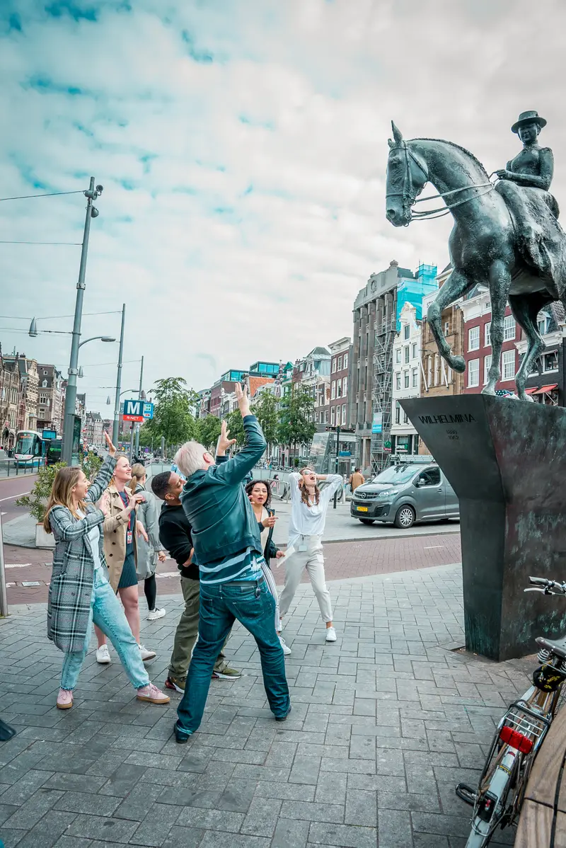 Group posing at a statue in Amsterdam during the Treasure Hunt team building